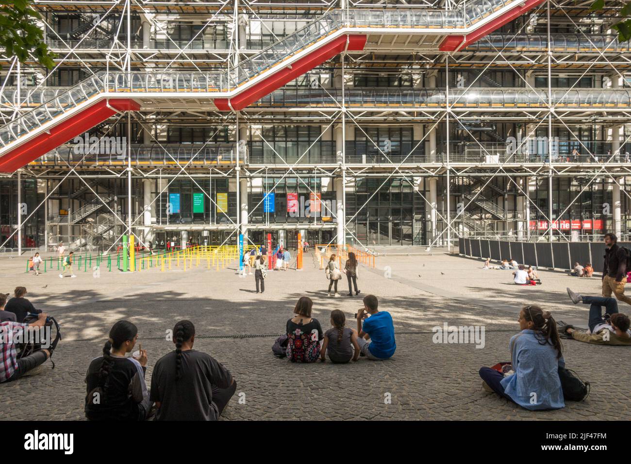 Touristes assis sur la place en face du Centre Georges Pompidou, place Georges Pompidou, Beaubourg. Paris, France. Banque D'Images
