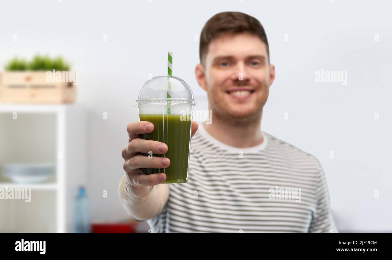 homme buvant du smoothie vert dans une tasse jetable Banque D'Images