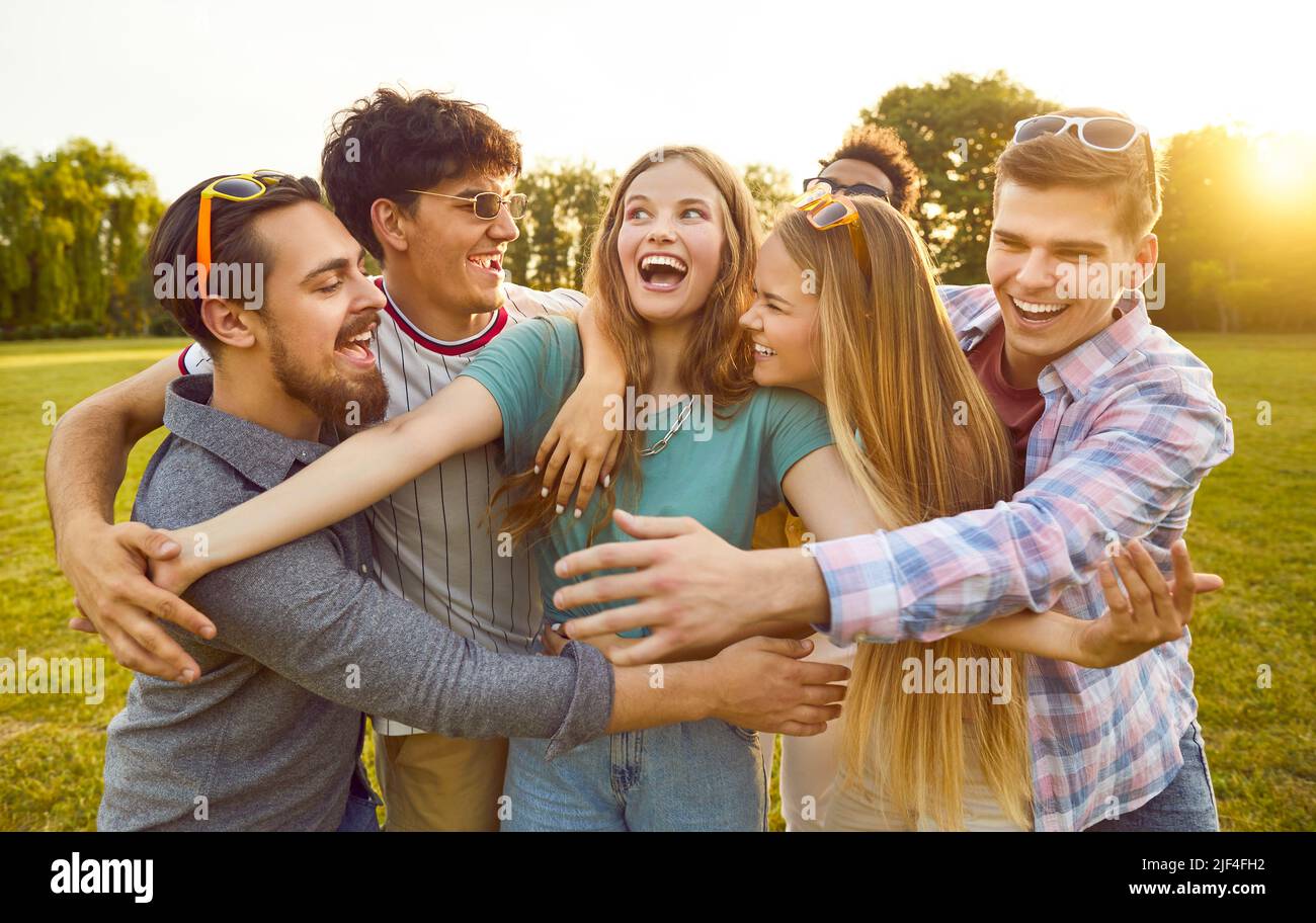 Groupe d'amis drôles, heureux, joyeux et excités qui s'embrasent et s'amusent dans le parc Banque D'Images