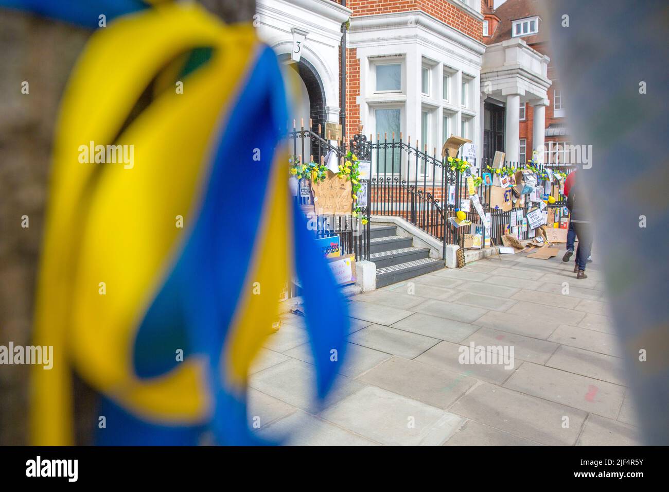 On voit des rubans bleus et jaunes attachés à un arbre tandis que les messages contre l’invasion de l’Ukraine par la Russie sont laissés près de l’ambassade de Russie à Londres. Banque D'Images