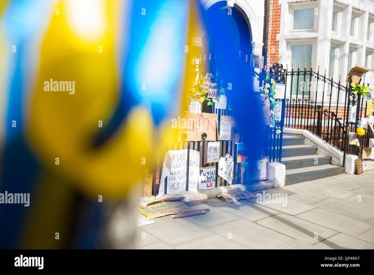 On voit des rubans bleus et jaunes attachés à un arbre tandis que les messages contre l’invasion de l’Ukraine par la Russie sont laissés près de l’ambassade de Russie à Londres. Banque D'Images