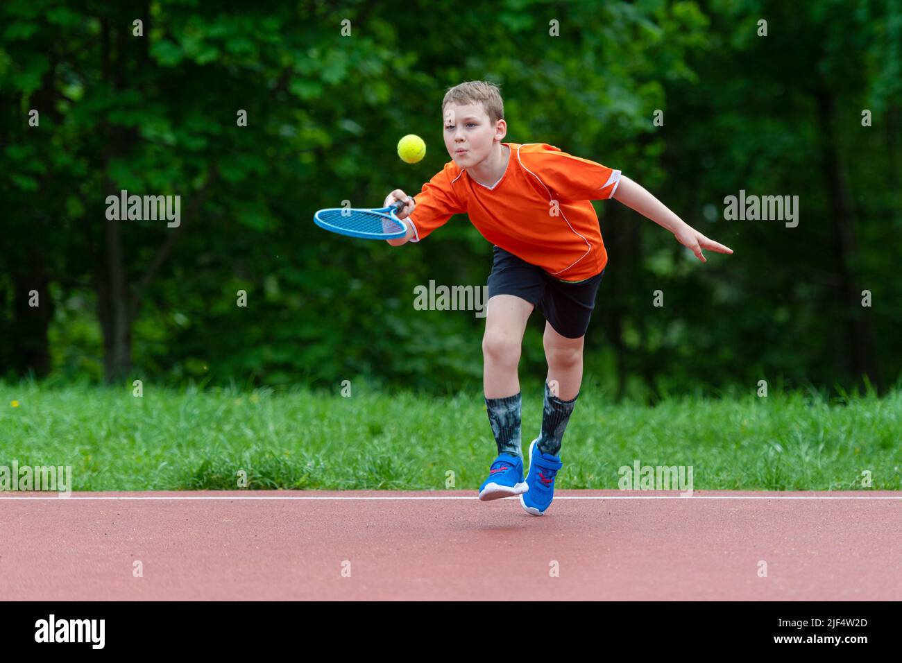 Enfant avec une raquette de tennis sur le court de tennis. Formation pour les jeunes enfants, enfants en bonne santé. Affiche horizontale sur le thème du sport, cartes de vœux, en-têtes, site Web et Banque D'Images