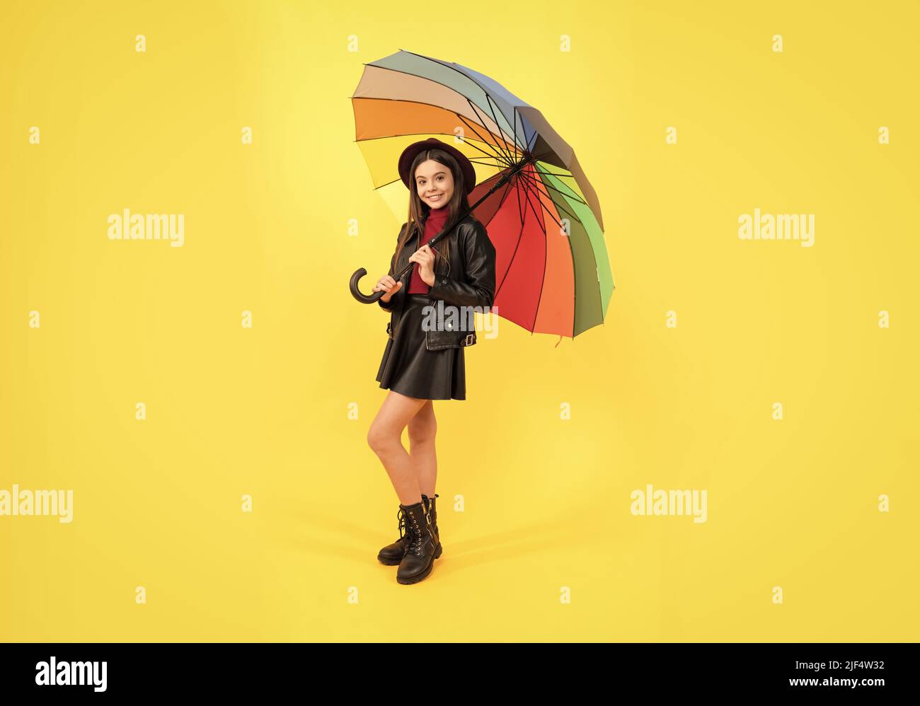 bonne jeune fille en chapeau et vêtements en cuir sous parapluie arc-en-ciel, temps d'automne Banque D'Images