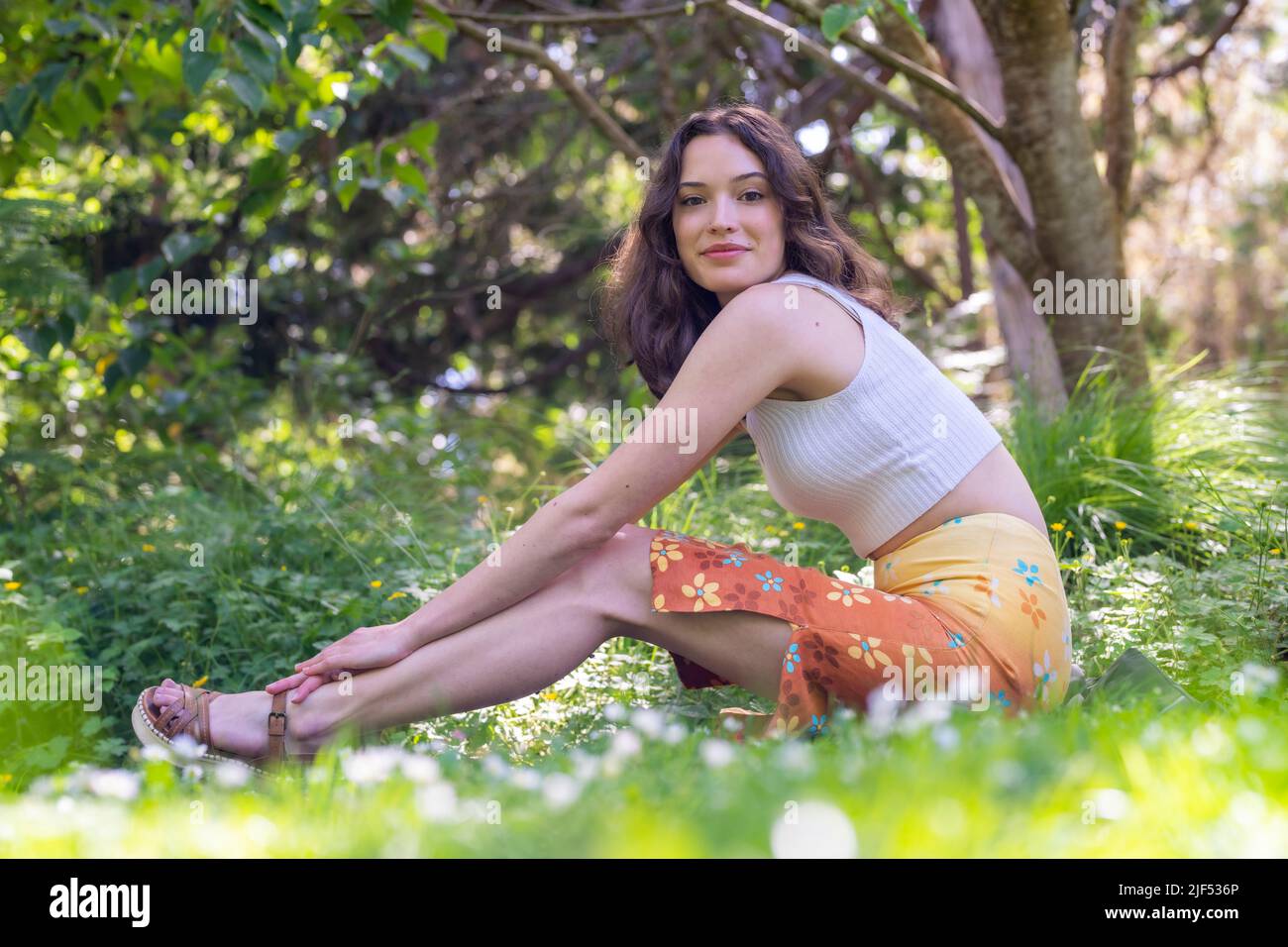 Portrait d'une jeune femme assise dans un jardin en jupe et brassière orange Banque D'Images