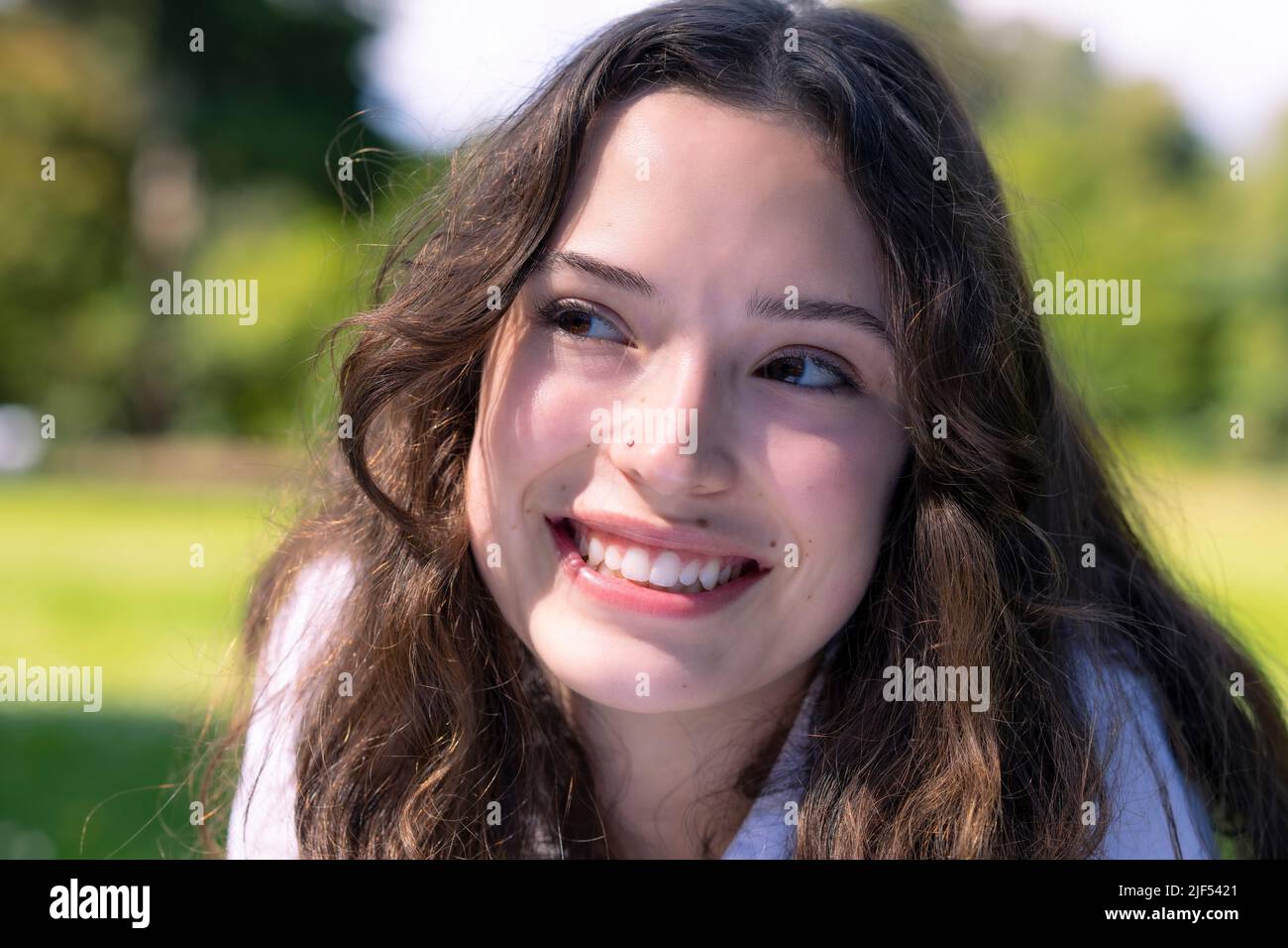 Portrait d'une jeune femme en décubitus ventral sur l'herbe dans un parc Banque D'Images