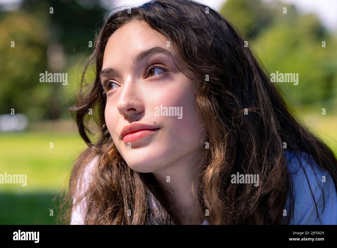 Portrait d'une jeune femme en décubitus ventral sur l'herbe dans un parc Banque D'Images