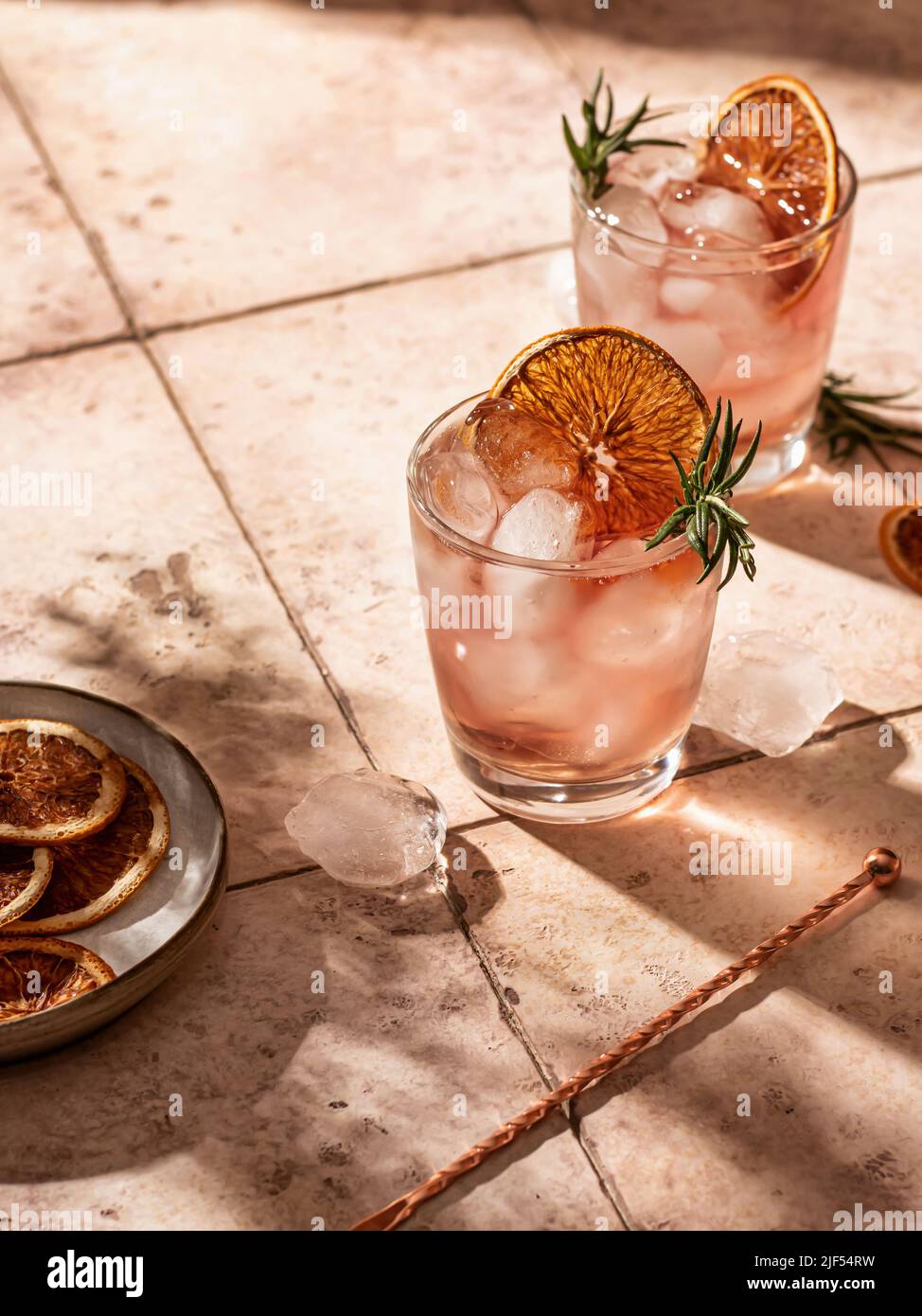 Cocktails d'été glacés à l'orange séché avec romarin et superbes ombres sur fond de carreaux. Orientation verticale Banque D'Images