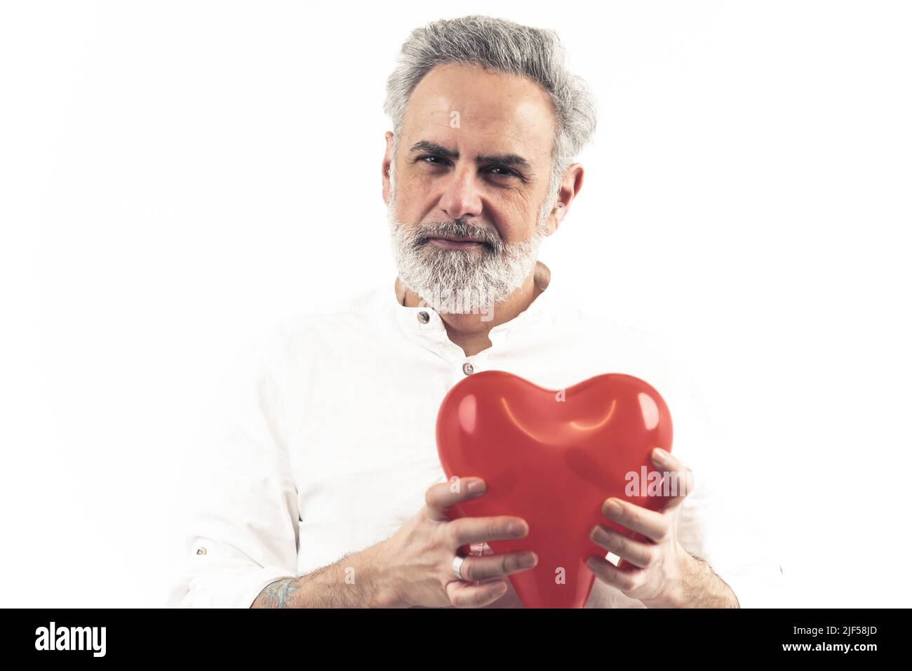L'homme caucasien à cheveux gris montre un ballon en forme de coeur, le tenant par coeur isolé blanc copie d'arrière-plan espace . Photo de haute qualité Banque D'Images