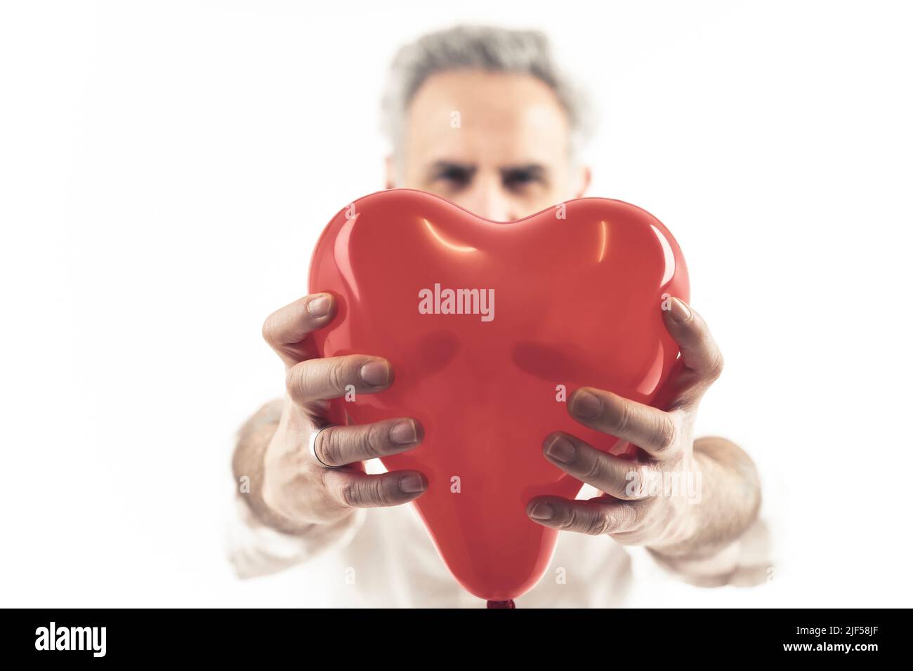 l'homme gris à cheveux d'âge moyen tient le ballon en forme de coeur isolé fond blanc moyen coup de feu . Photo de haute qualité Banque D'Images