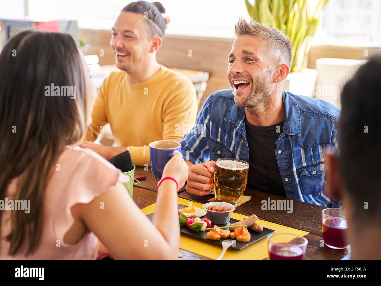 Des amis heureux s'amuser ensemble dans un bar en buvant de la bière et en prenant des hors-d'œuvre. Les jeunes ont un style de vie dans une fête de jour Banque D'Images