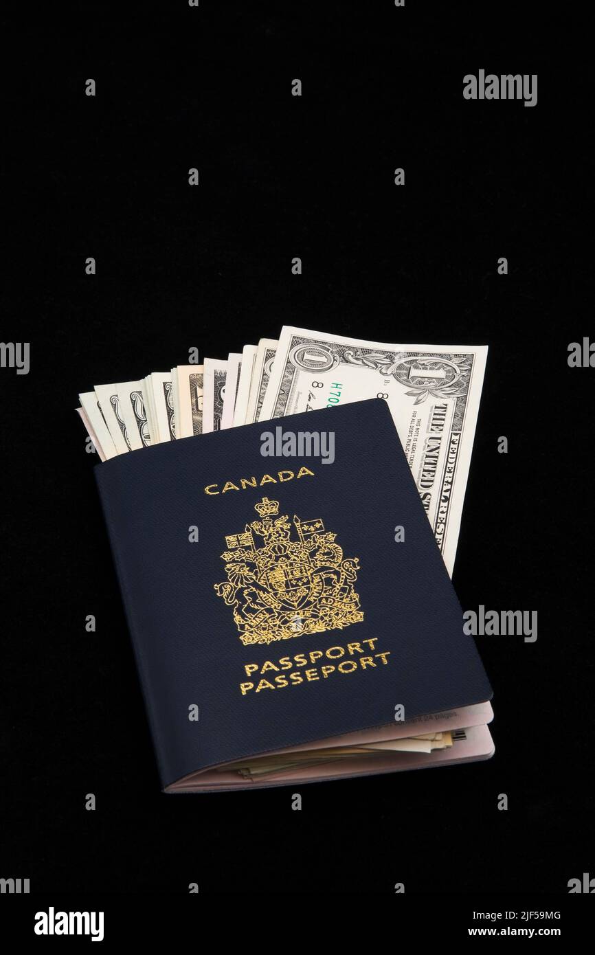 BILLETS de banque EN devise AMÉRICAINE à l'intérieur du passeport canadien sur fond noir. Banque D'Images