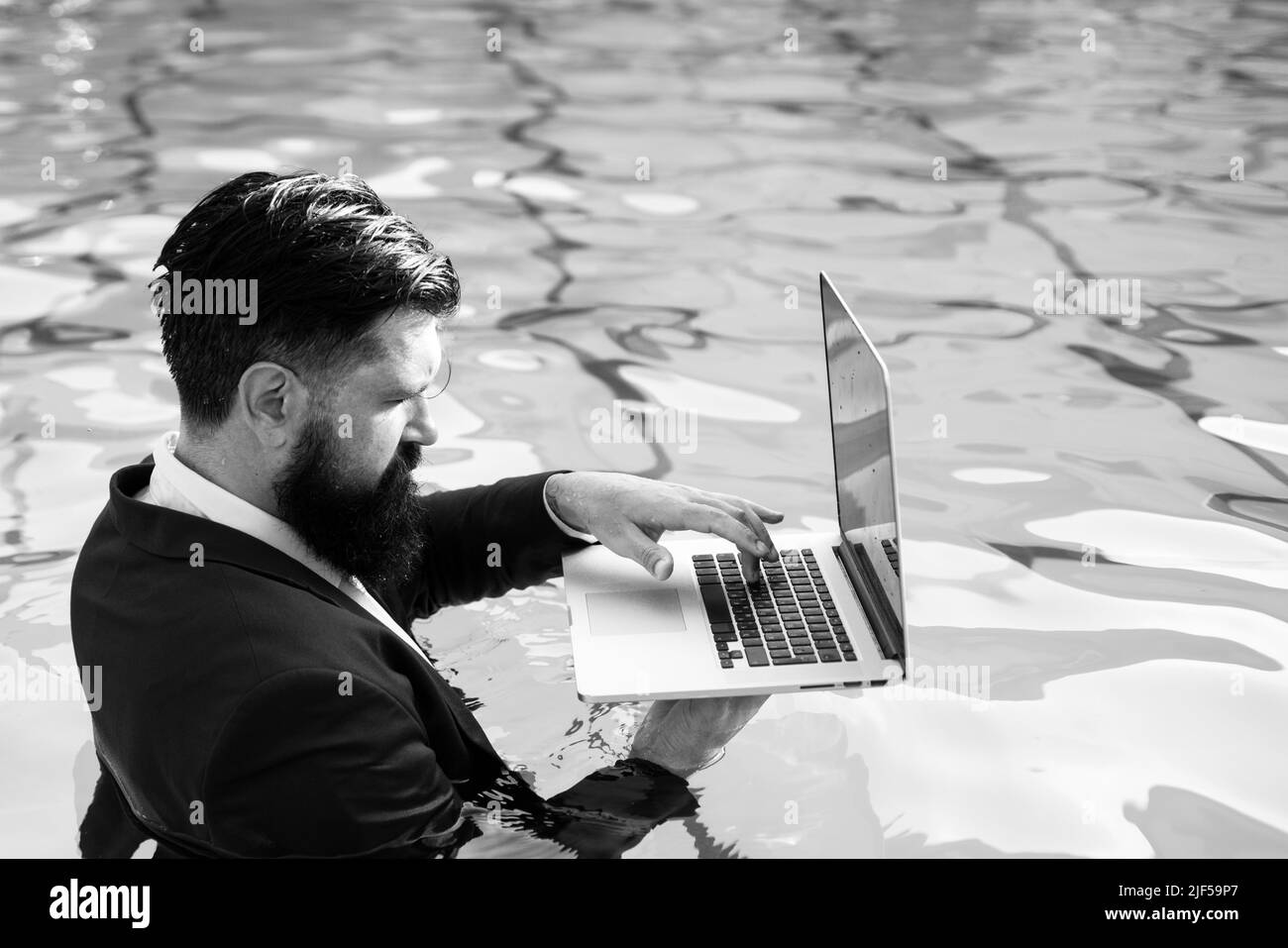 Homme d'affaires en costume avec ordinateur portable sur la piscine. Banque D'Images