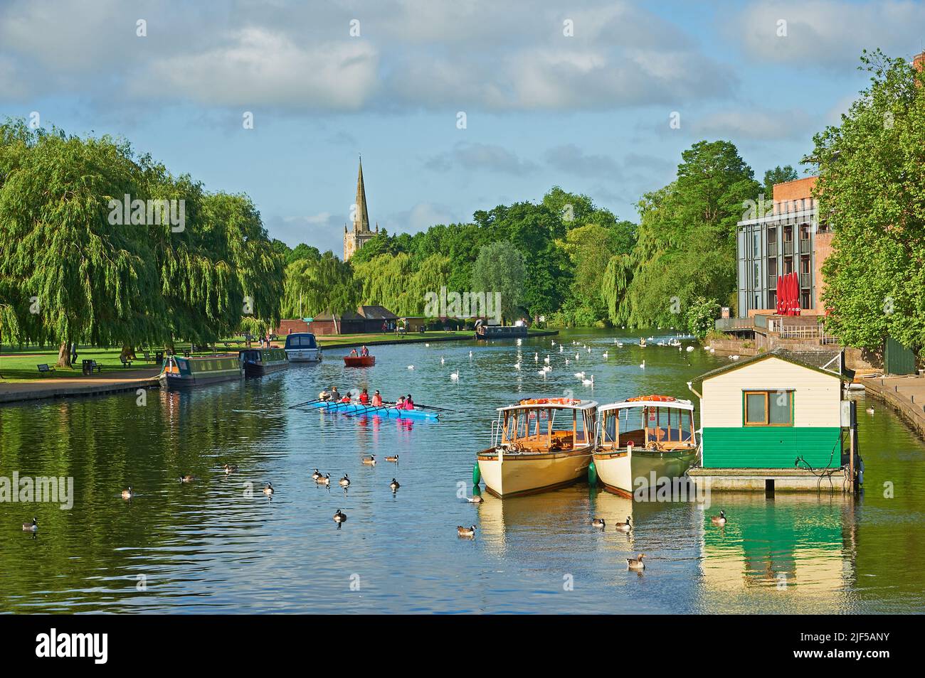 Vue le long de la rivière Avon, Stratford-upon-Avon, Warwickshire vers l'église de la Sainte-Trinité, avec des bateaux d'excursion d'une journée de tourisme amarrés. Banque D'Images