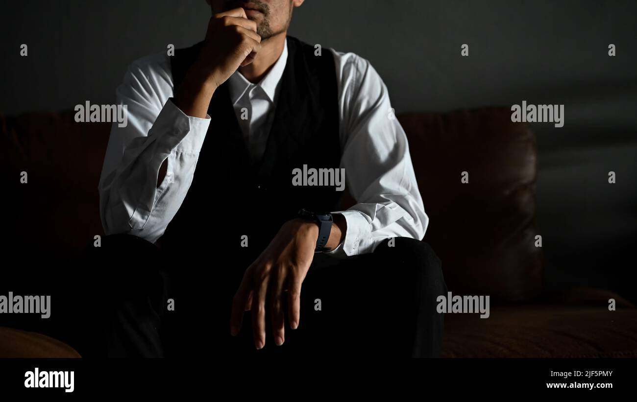 Homme d'affaires asiatique professionnel et réussi ou directeur général masculin dans un costume formel se trouve sur un canapé en cuir dans une posture pensive d'expression de pensée Banque D'Images