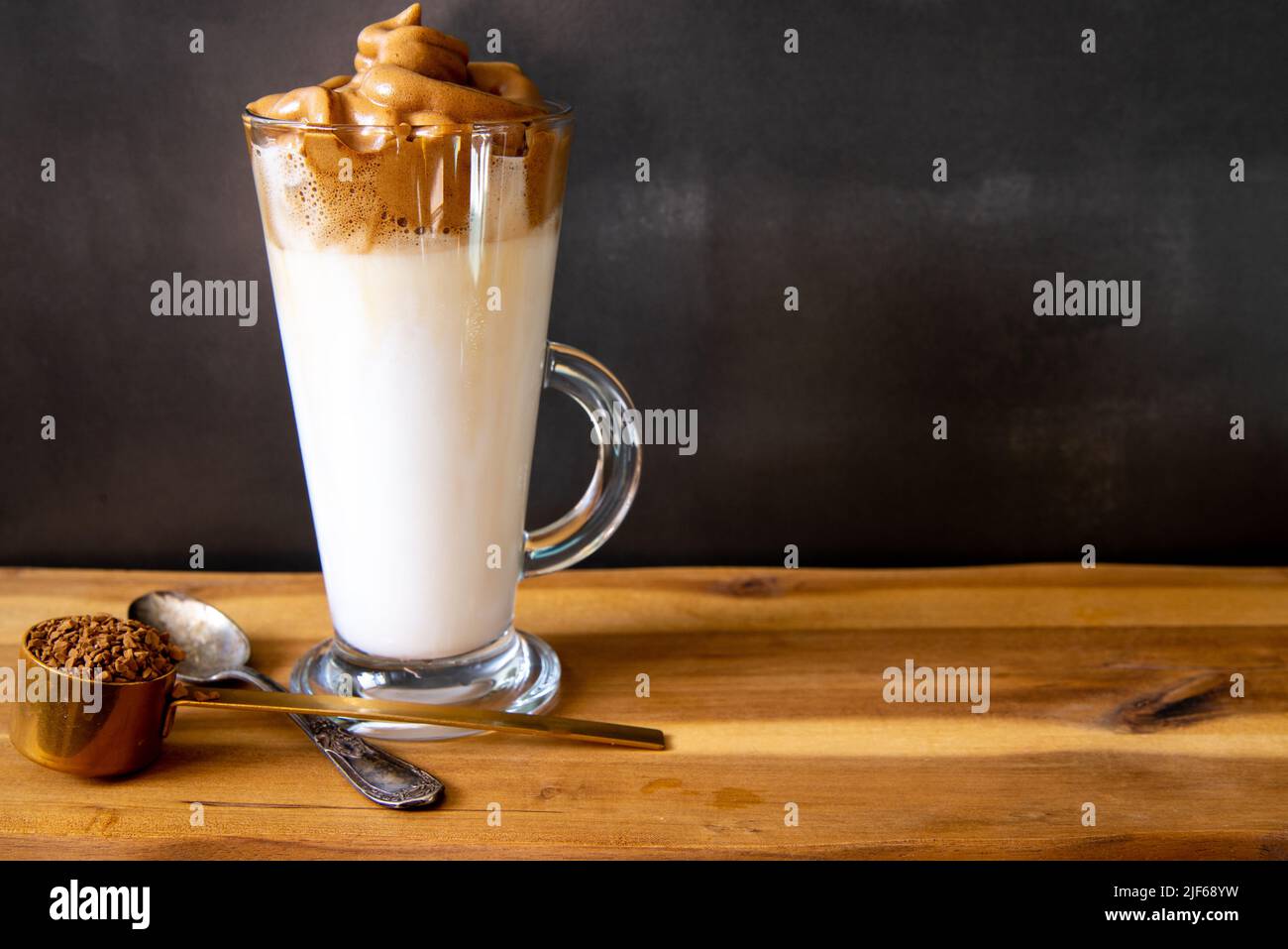 Café Dalgona. Boisson glacée au café de style coréen sur fond sombre. Café instantané fouetté avec du sucre et de l'eau pour un petit déjeuner savoureux. Très tendance co Banque D'Images