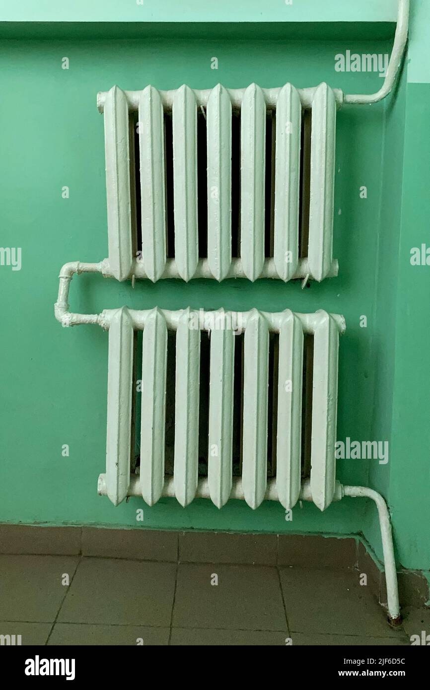 Radiateur à eau en fonte à l'ancienne avec tuyaux dans le couloir ou le salon dans le style de l'Union soviétique. Bâtiment de chauffage, maison de l'hiver. Tir vertical. CLO Banque D'Images