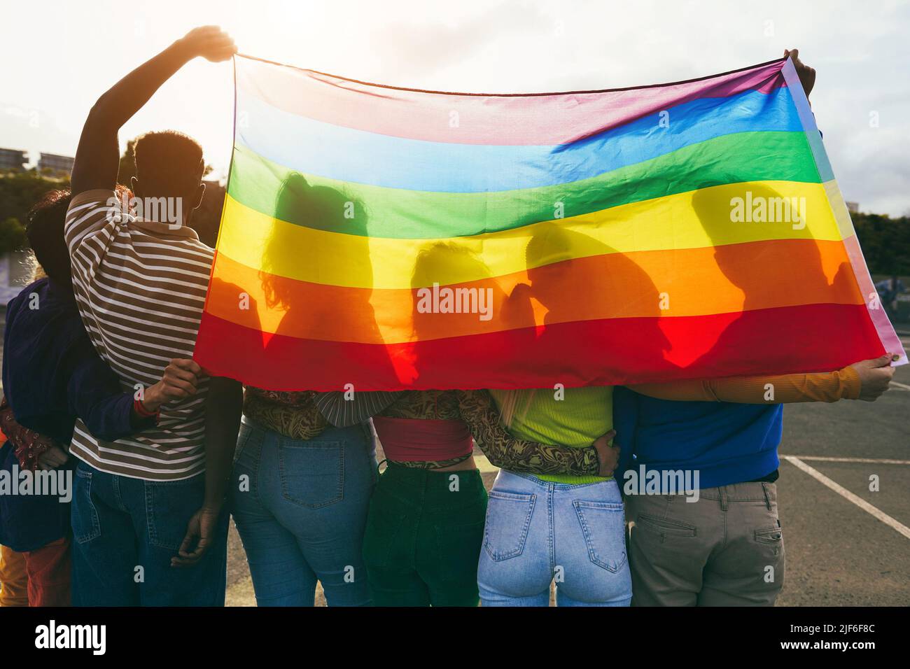 Jeunes diverses personnes ayant le plaisir de tenir le drapeau arc-en-ciel lgbt en plein air - foyer principal sur le gars africain de retour Banque D'Images