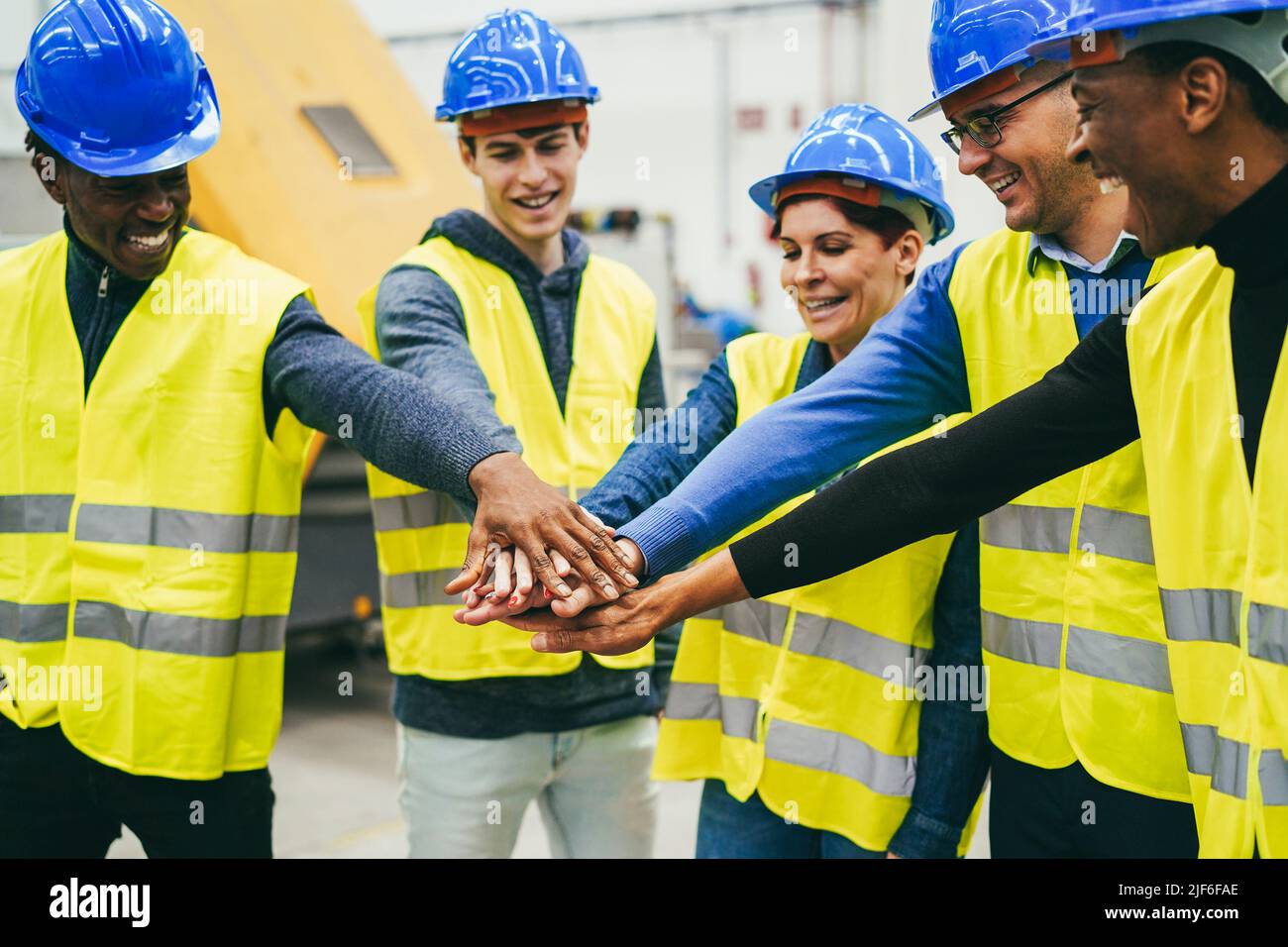 Les ingénieurs multiraciaux empilent les mains dans l'usine robotique - concentrez-vous sur les mains Banque D'Images