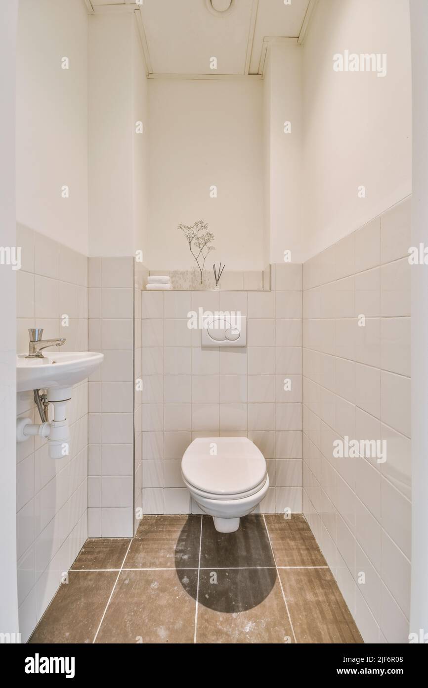toilettes murales et petit lavabo dans le coin des toilettes chambre avec carrelage beige Banque D'Images