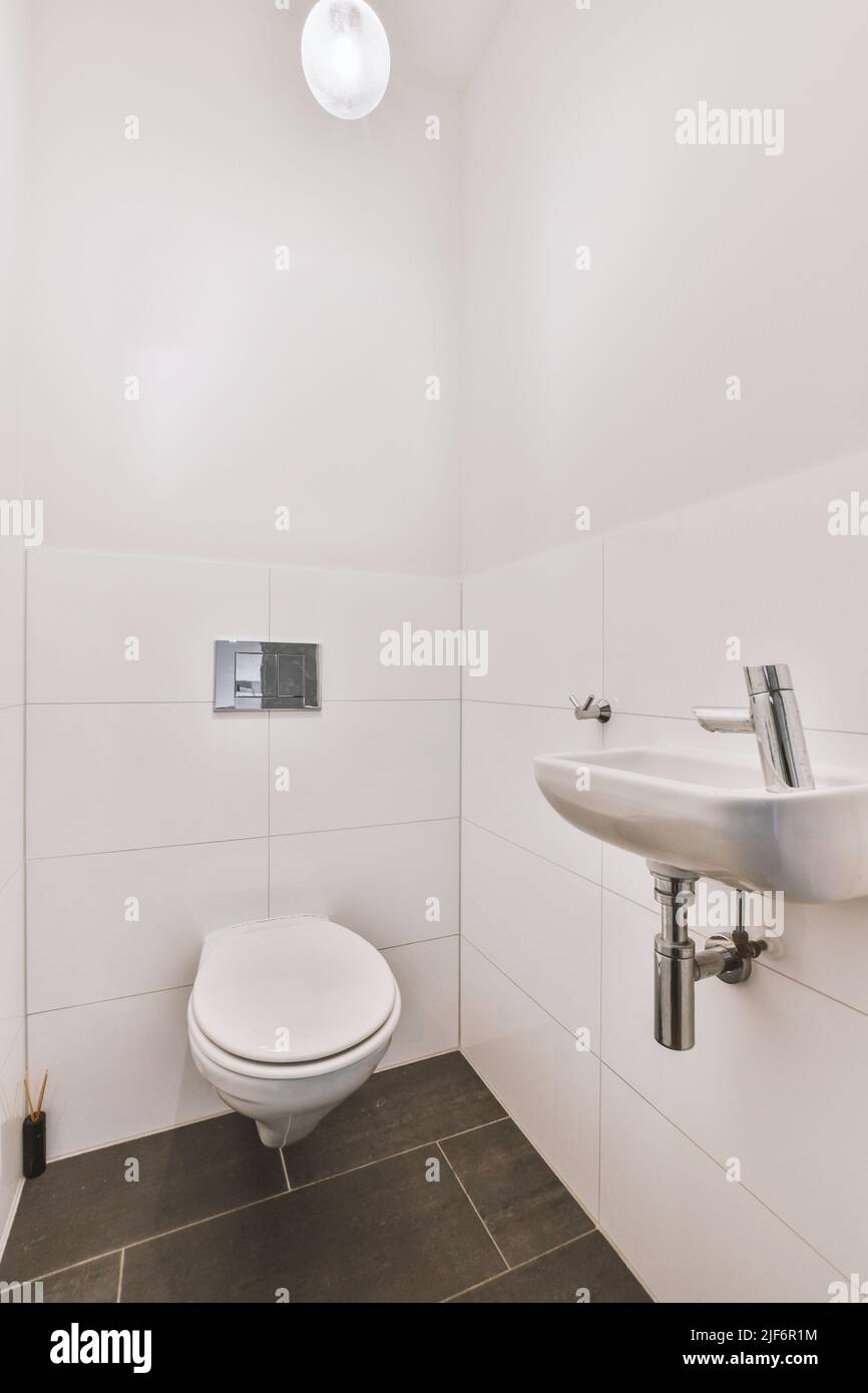 toilettes accrochées au mur et petit lavabo dans le coin de la salle de toilette avec carrelage Banque D'Images