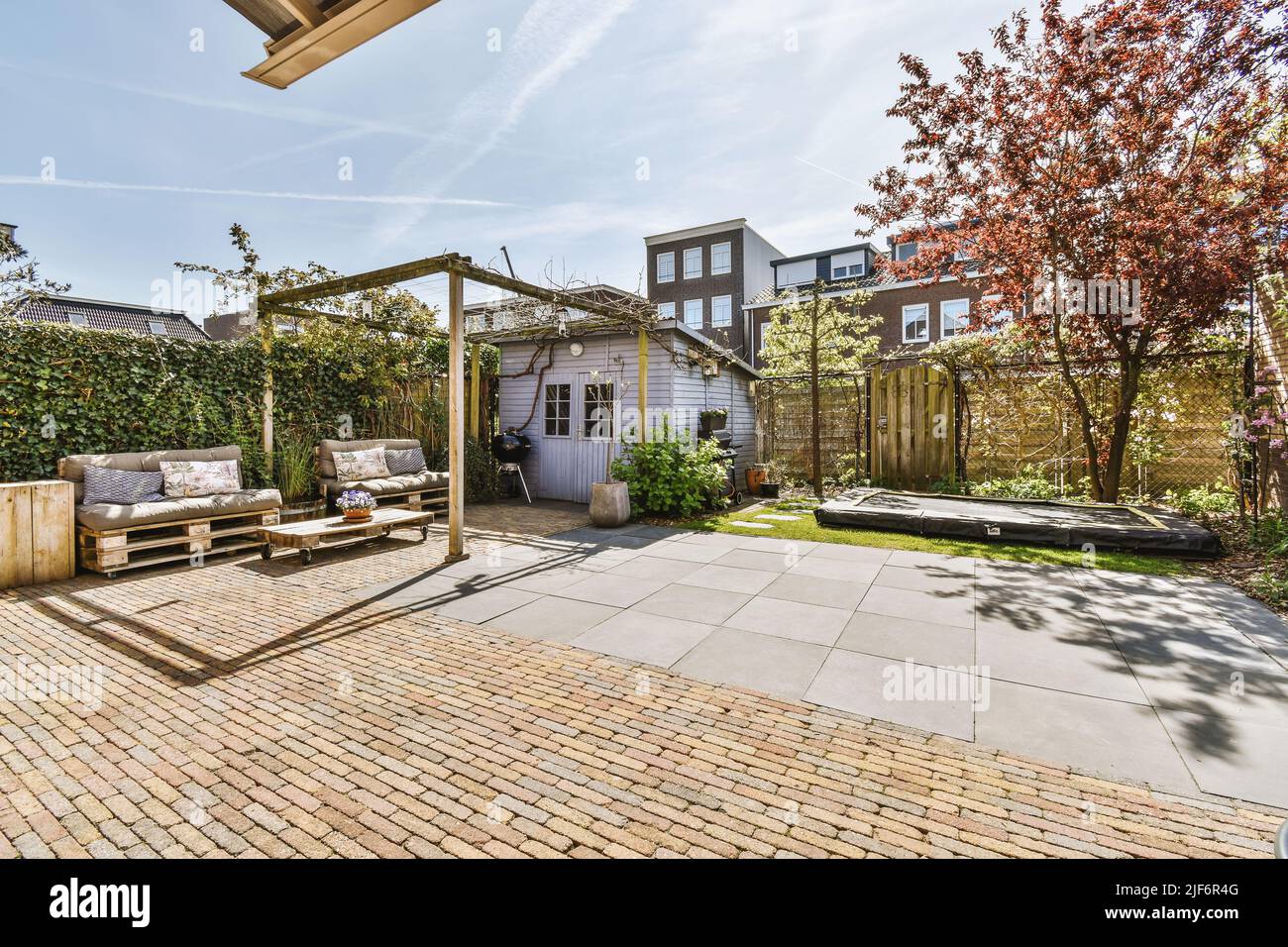 Beau patio pavé avec coin salon et petit jardin près de la clôture en bois Banque D'Images