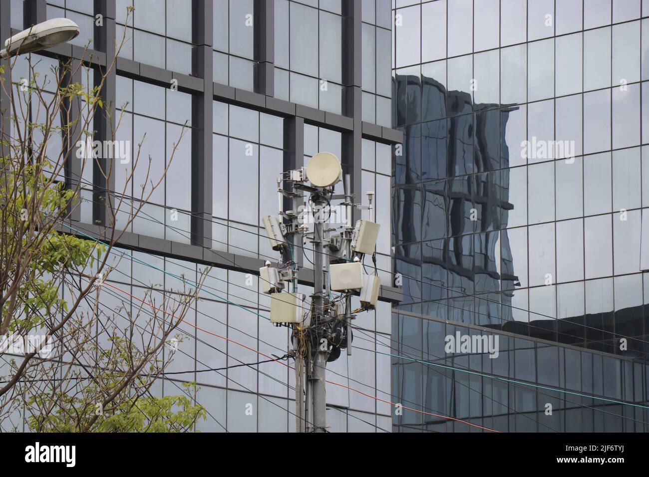 Antenne RF et antenne micro-ondes sur une petite tour devant un bâtiment en verre Banque D'Images