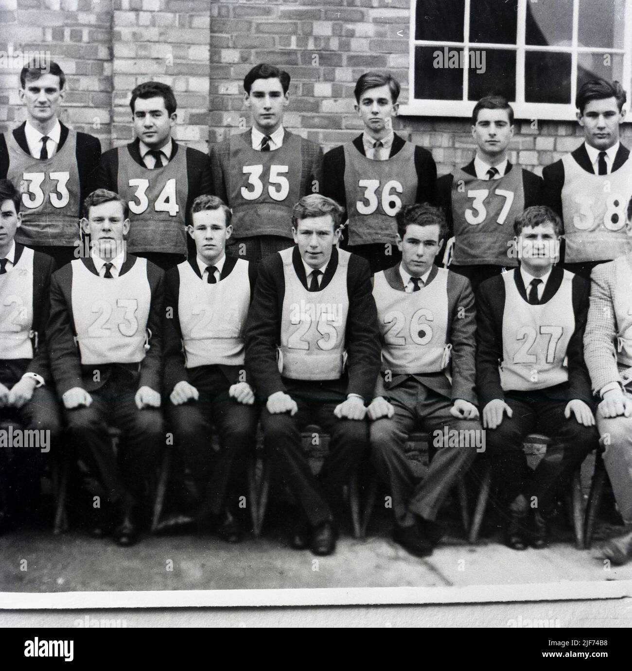 1950s, historique, un groupe d'apprentis ingénieurs en acier de sexe masculin dans des bibs numérotés se sont réunis pour une photo à l'extérieur, Abbey Works, Port Talbot, pays de Galles, Royaume-Uni. Banque D'Images