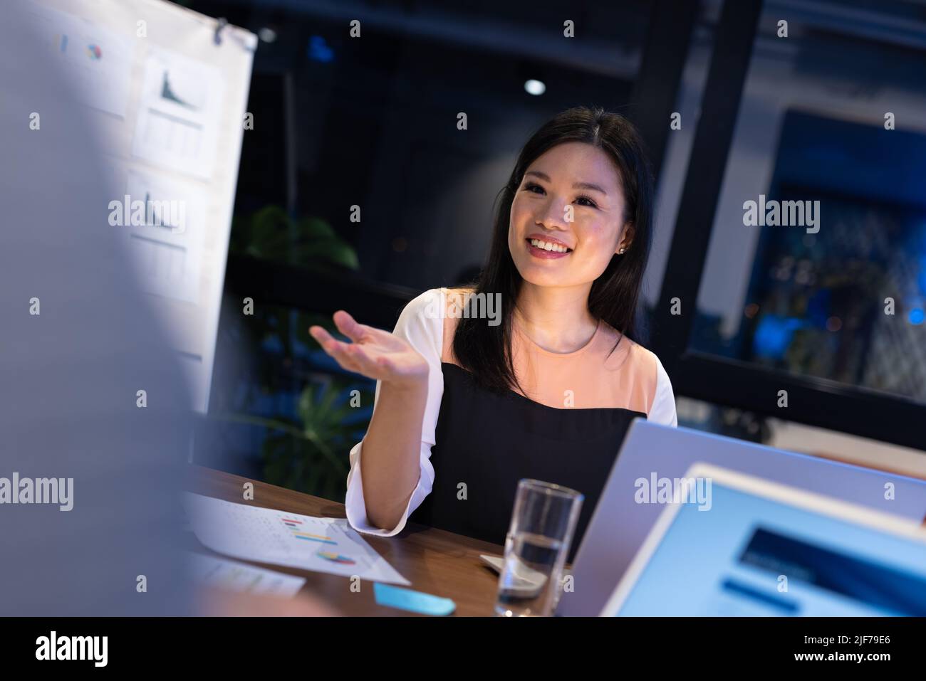 Femme d'affaires asiatique souriante qui se fait des gestuelle et communique tout en étant assise à table dans la salle de réunion Banque D'Images