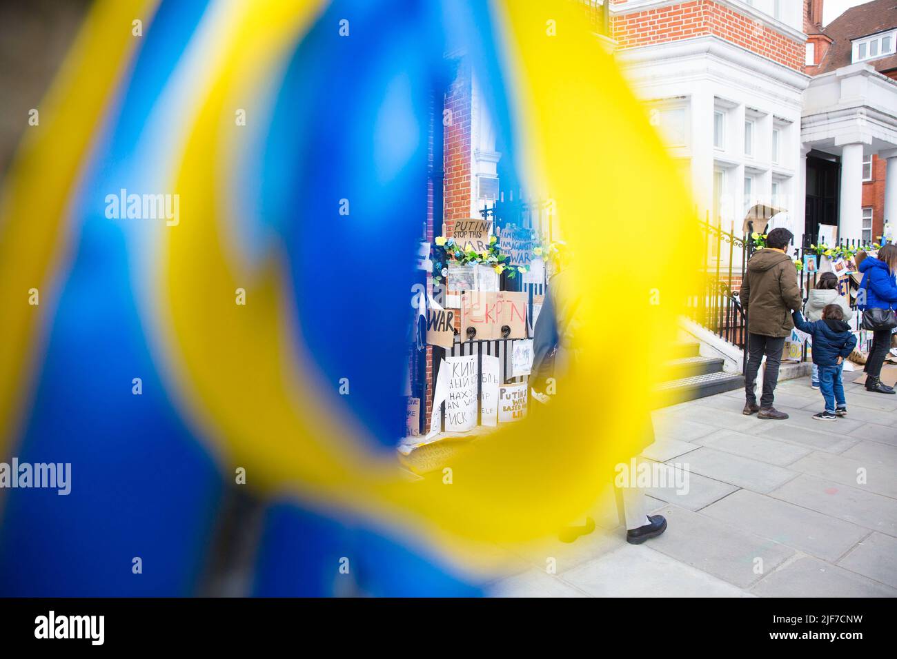 Derrière des rubans bleus et jaunes attachés à un arbre, des messages et des affiches contre l’invasion de l’Ukraine par la Russie sont laissés près de l’ambassade de Russie à Londres. Banque D'Images