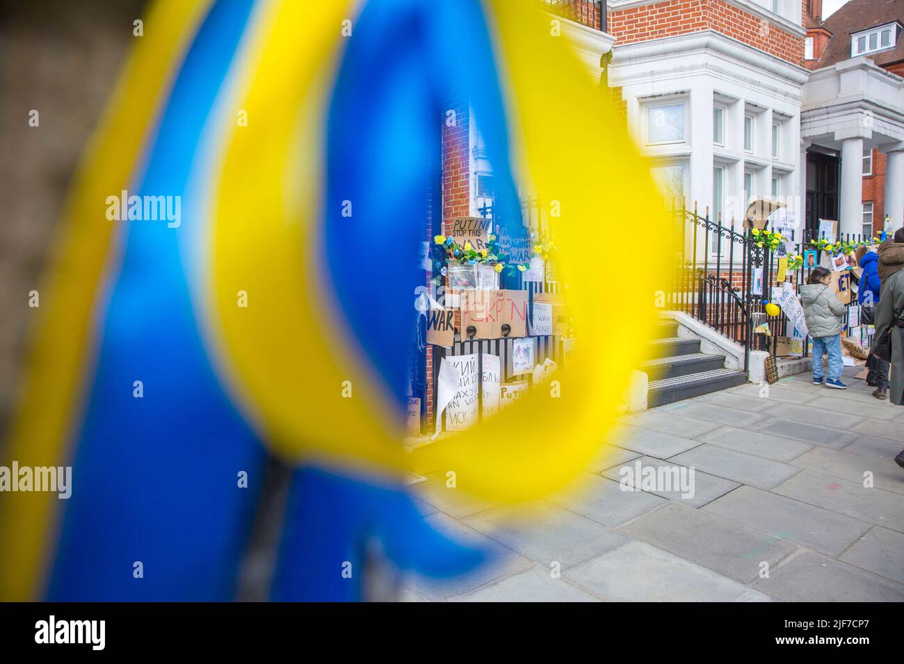Derrière des rubans bleus et jaunes attachés à un arbre, des messages et des affiches contre l’invasion de l’Ukraine par la Russie sont laissés près de l’ambassade de Russie à Londres. Banque D'Images