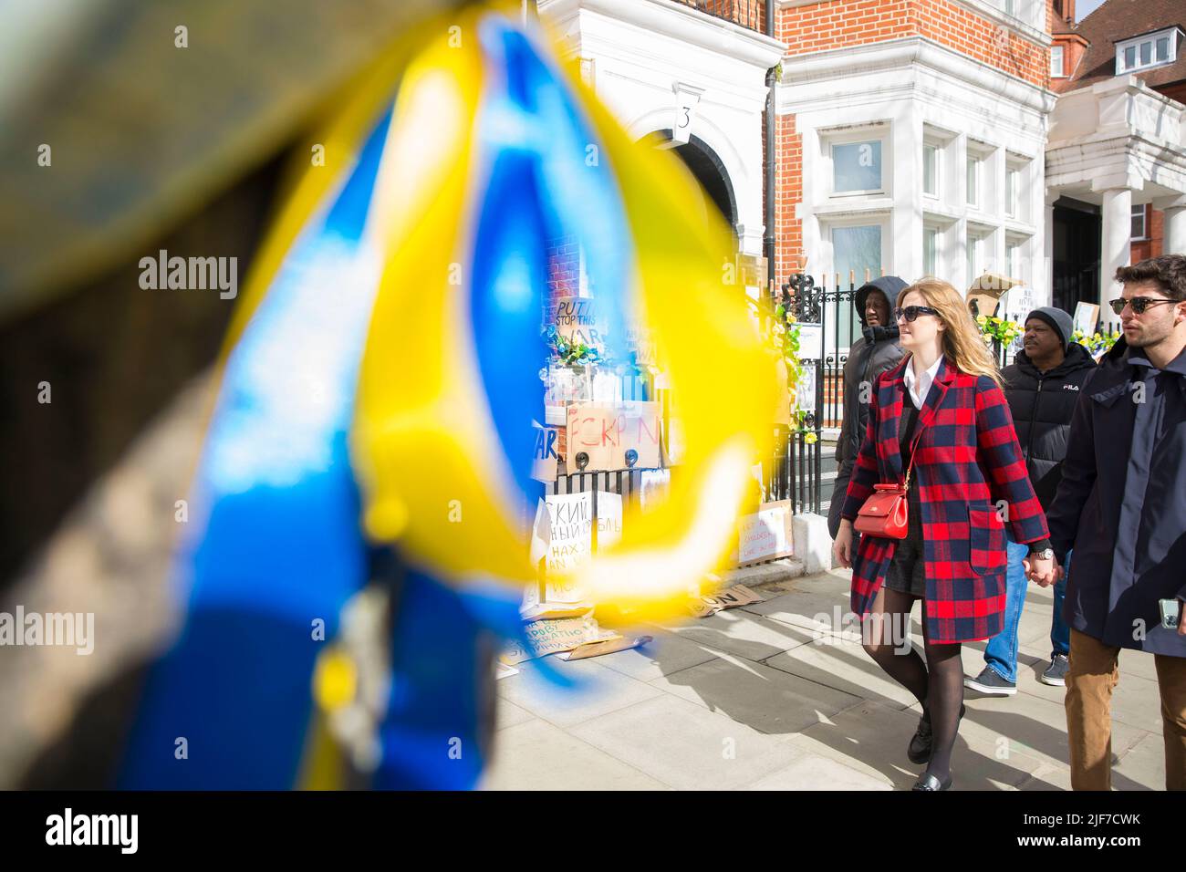 Derrière des rubans bleus et jaunes attachés à un arbre, des messages et des affiches contre l’invasion de l’Ukraine par la Russie sont laissés près de l’ambassade de Russie à Londres. Banque D'Images