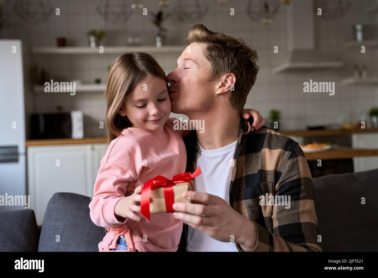 Joyeux enfant adorable fille embrassant papa faisant cadeau à la maison le jour des Pères. Banque D'Images