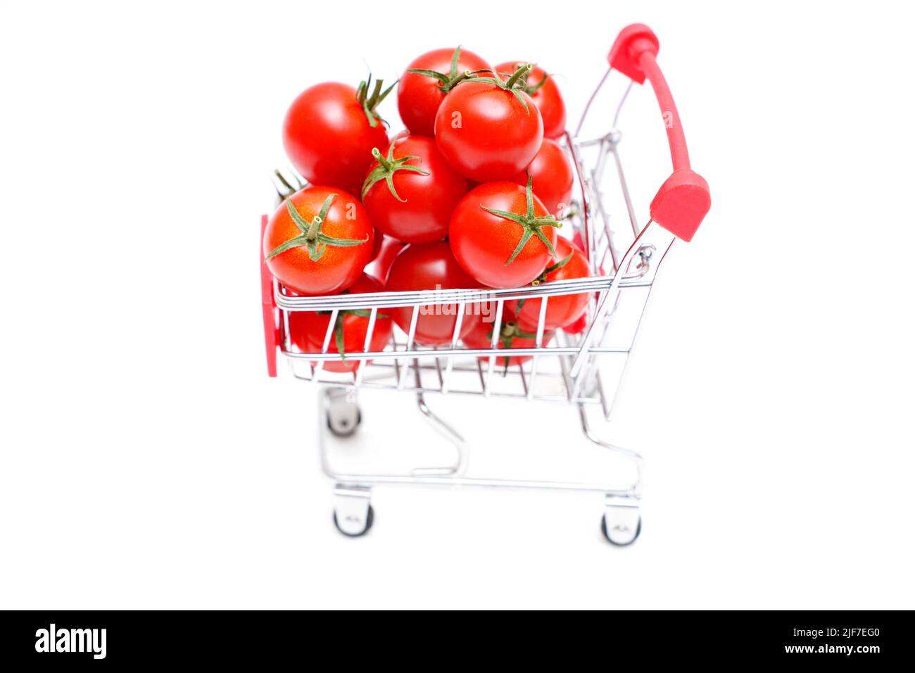 Chariot de poussée de jouet plein de tomates fraîches de cocktail isolées sur fond blanc. Banque D'Images