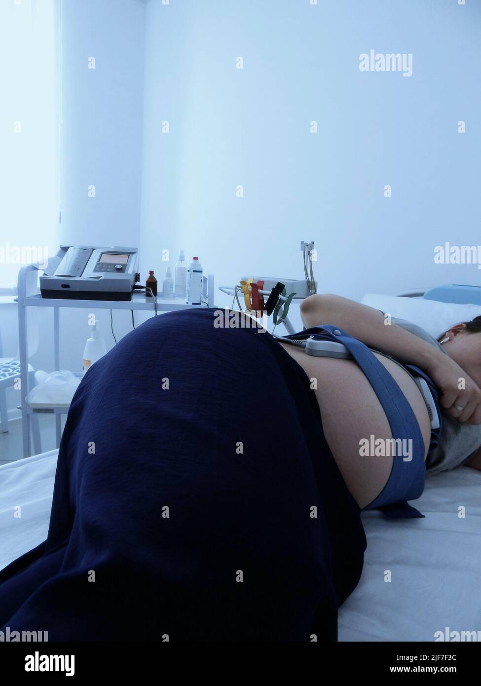 Femme enceinte au repos pendant que le moniteur CTG enregistre le rythme cardiaque fœtal Banque D'Images
