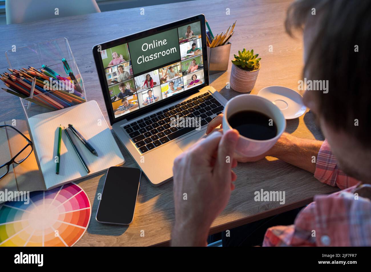 Un professeur caucasien tenant une tasse de café enseignant en ligne sur ordinateur portable par appel vidéo à la maison Banque D'Images