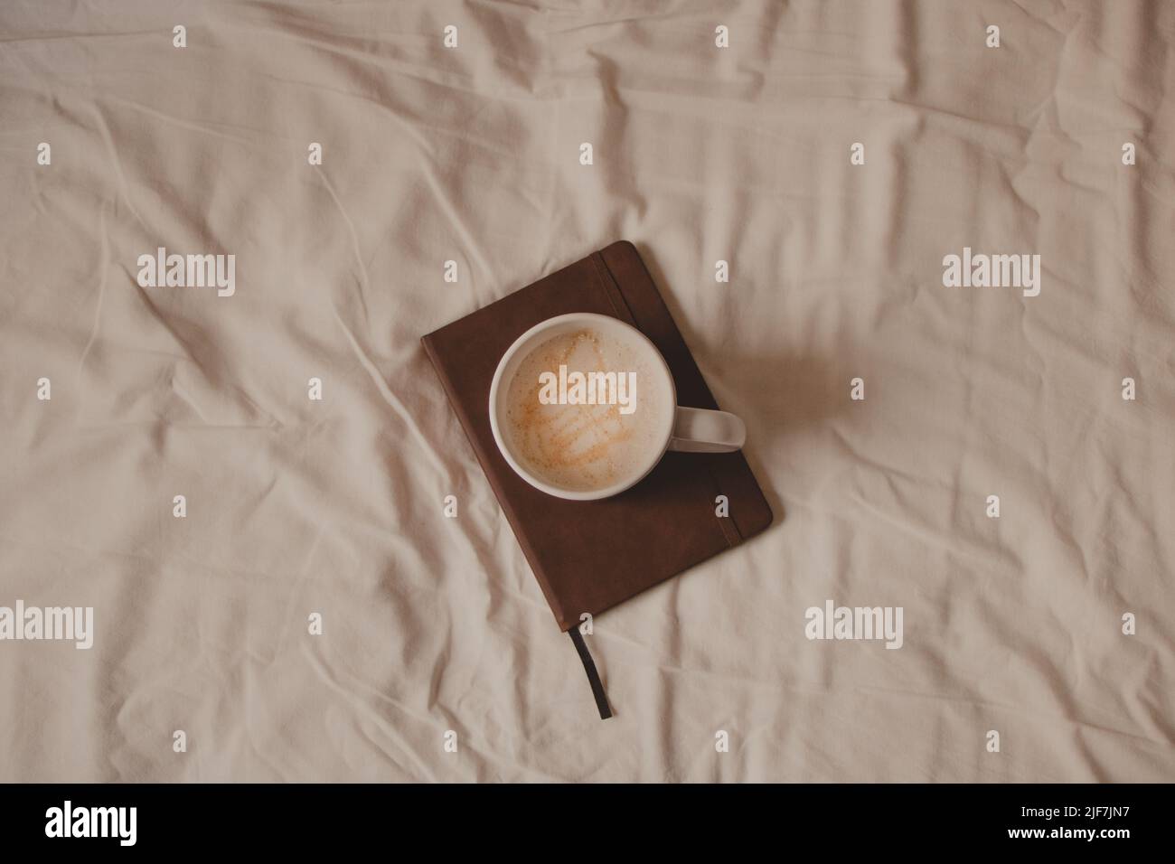 concept minimaliste lit confortable avec café et un carnet marron Banque D'Images