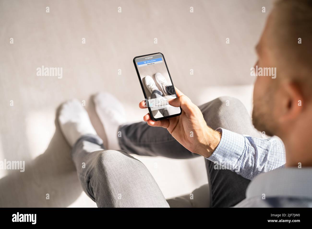 Homme essayant des baskets virtuelles dans Shop ou Store AR App Banque D'Images Homme essayant des baskets virtuelles dans Shop ou Store AR App Banque D'Images