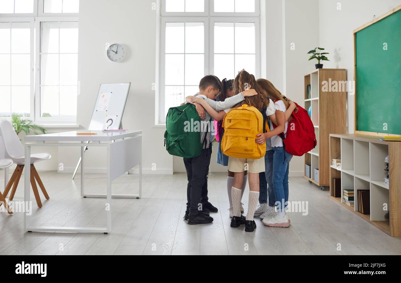 Groupe de petits amis de l'école se tenant ensemble dans la salle de classe et s'embrassant les uns les autres Banque D'Images