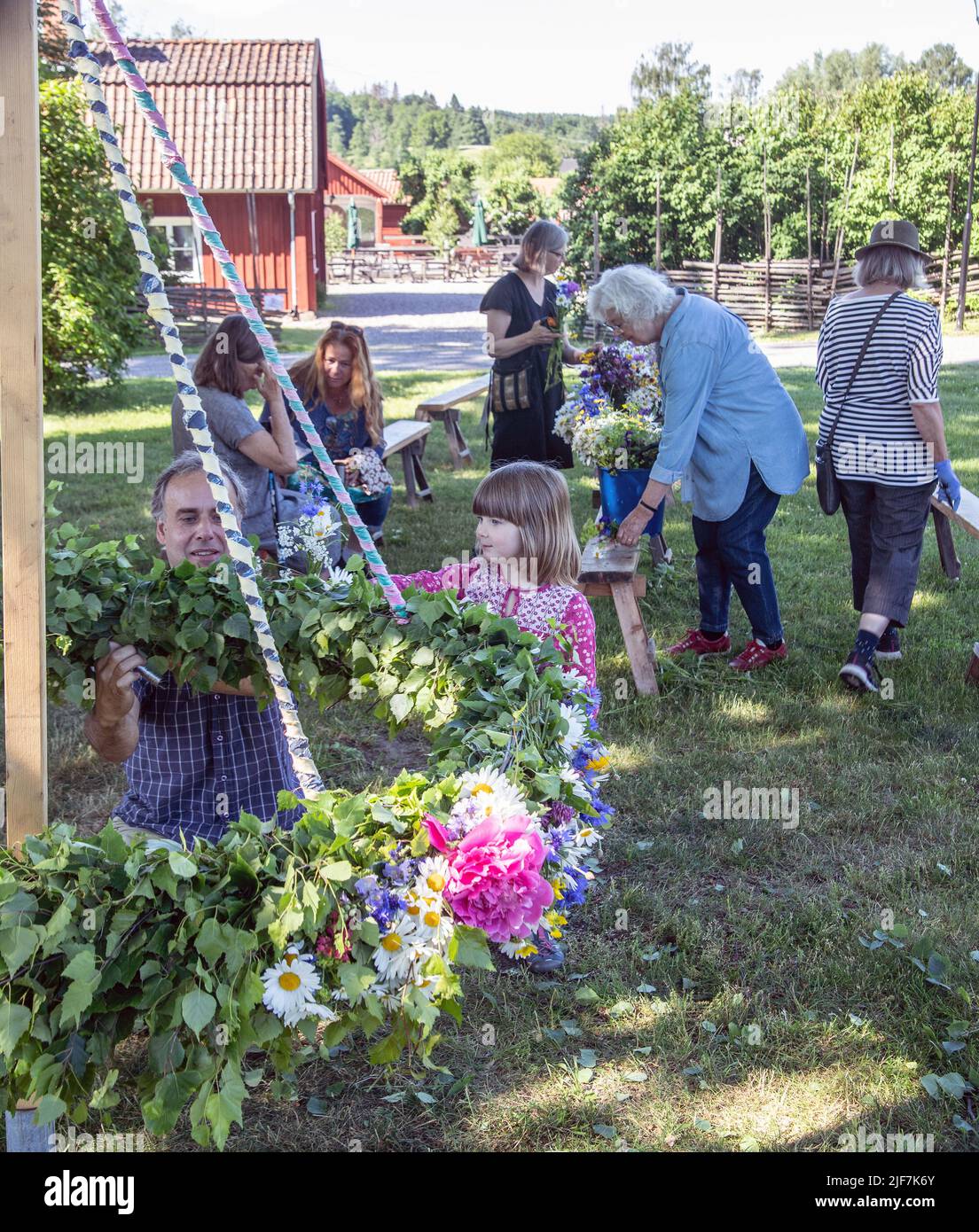 Au milieu de l'été en Suède, parents et enfants nouent des fleurs sur une grande couronne à malmkoping, en Suède Banque D'Images