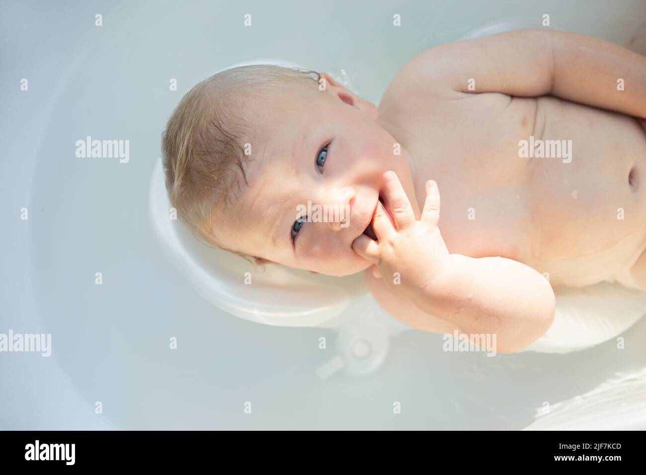 mignon bébé à yeux bleus de 6 mois baigné dans un bain de bébé Banque D'Images