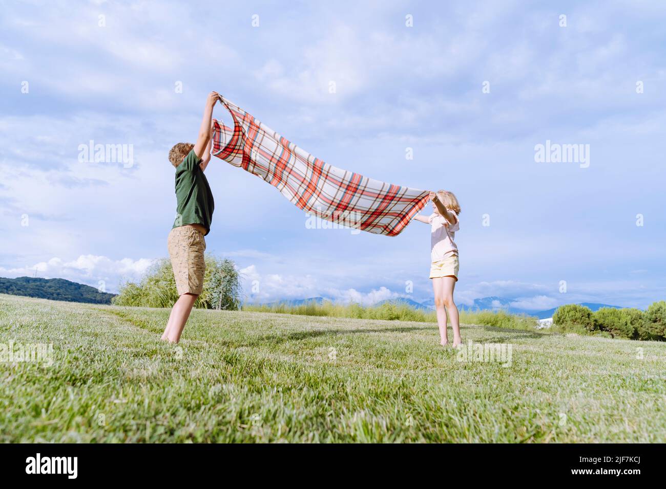 ?hildren pose une couverture de pique-nique dans un champ sur l'herbe. Banque D'Images