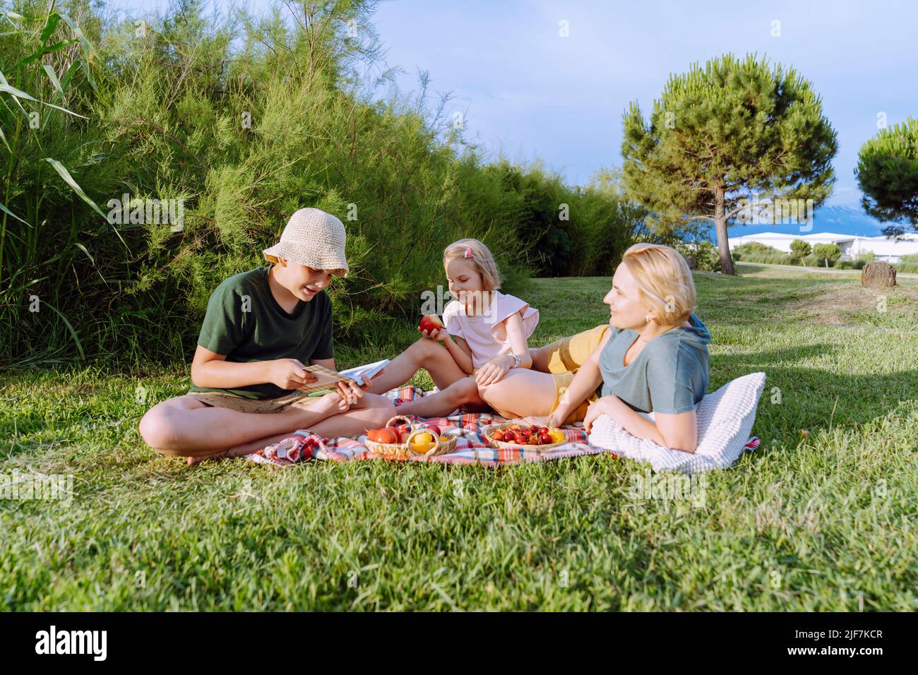 Les parents et les enfants ont un pique-nique et lisent un livre. Banque D'Images