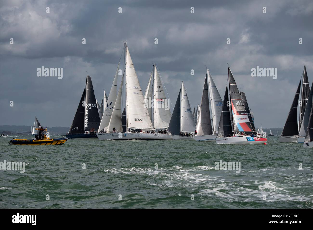 Les concurrents font la queue et passent le bateau de patrouille du port jaune pour démarrer la course annuelle de yacht Round the Island du Club de voile de l'île de Wight Banque D'Images