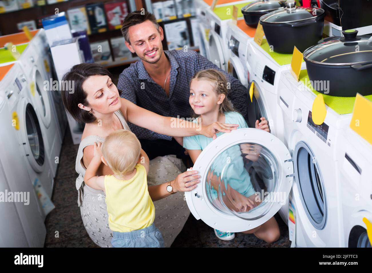 Bonne famille de quatre personnes choisissant la machine à laver Banque D'Images
