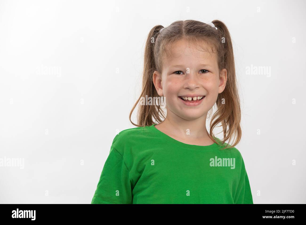 Petite fille souriante dans un t-shirt vert sur fond blanc Banque D'Images