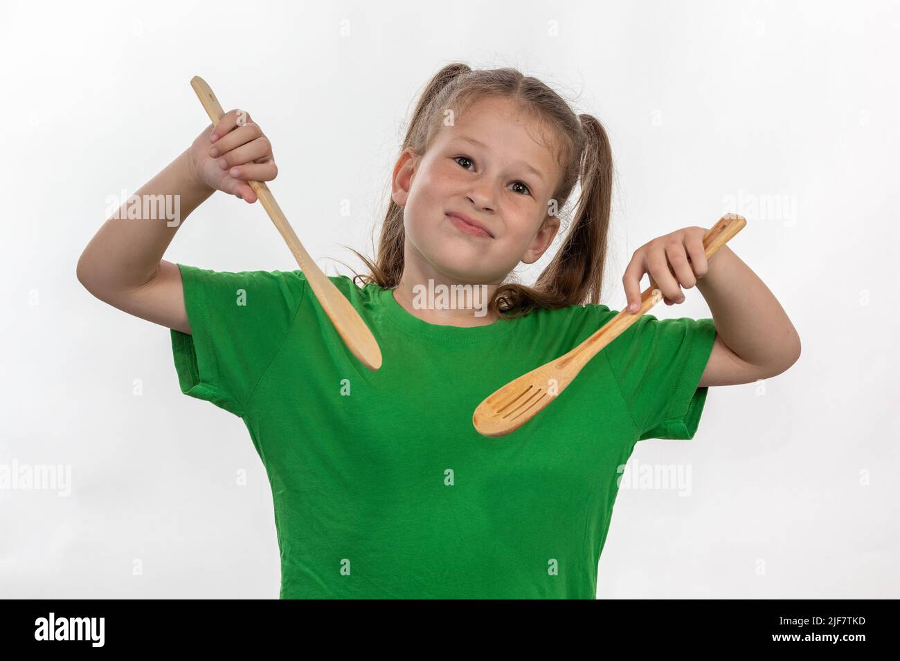 Une jeune fille montre qu'elle aime cuisiner avec ses cuillères de cuisson en bois Banque D'Images