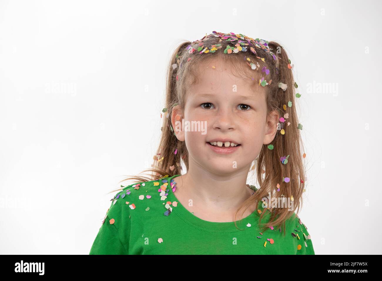 Portrait d'un enfant après une pluie confetti avec des guirlandes multicolores et des confettis. S'amuser à célébrer son anniversaire. Banque D'Images