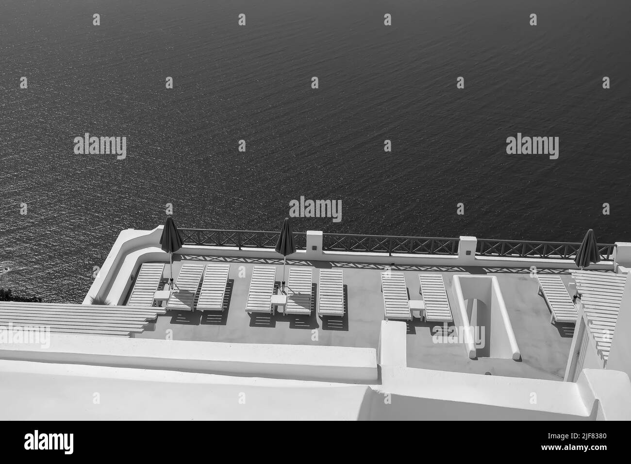 Une belle terrasse blanchie à la chaux avec chaises longues et une vue à couper le souffle sur la mer Égée à Santorini Grèce en noir et blanc Banque D'Images