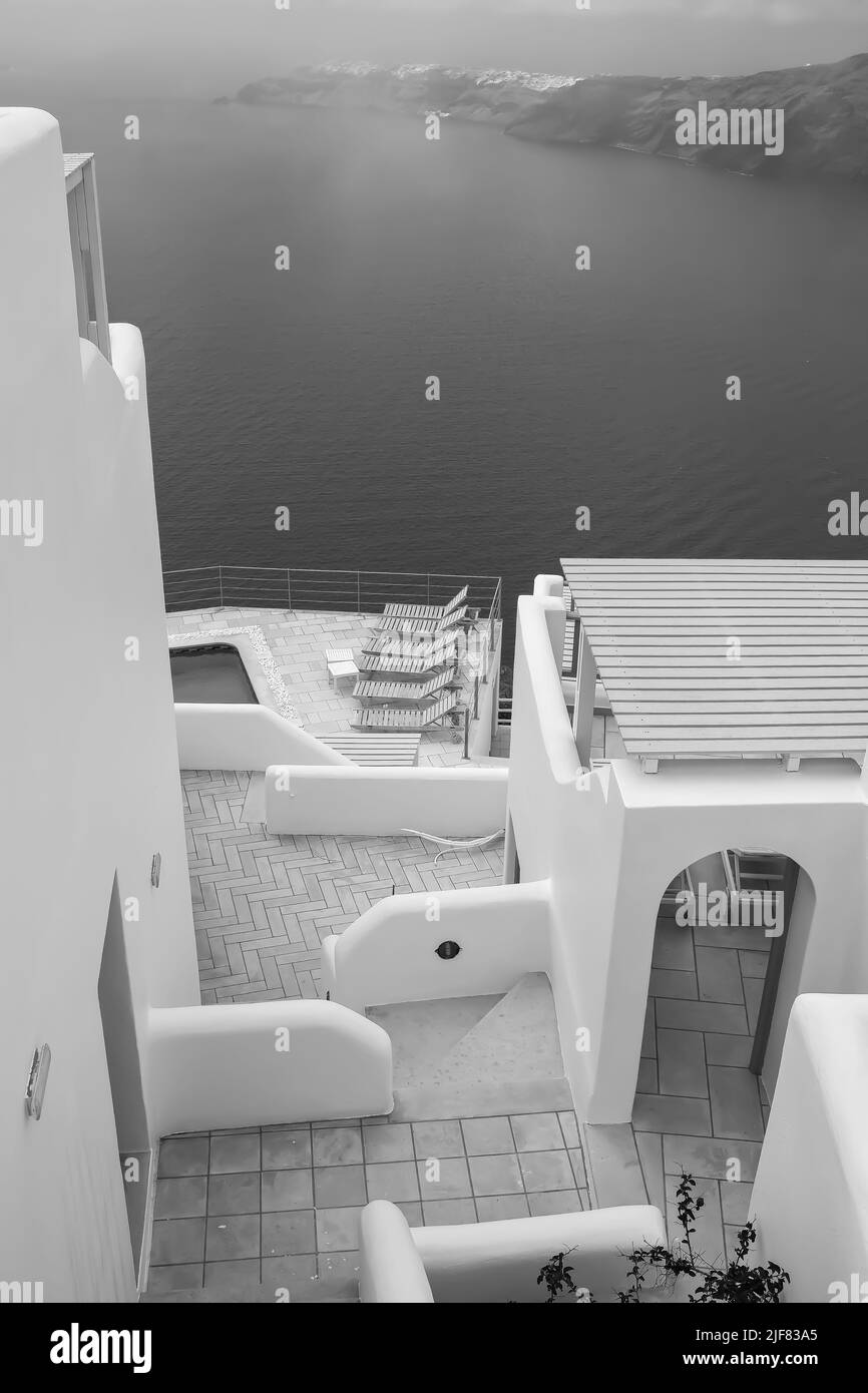 Une belle terrasse avec chaises longues, une piscine et une vue imprenable sur la mer Égée à Santorini Grèce en noir et blanc Banque D'Images
