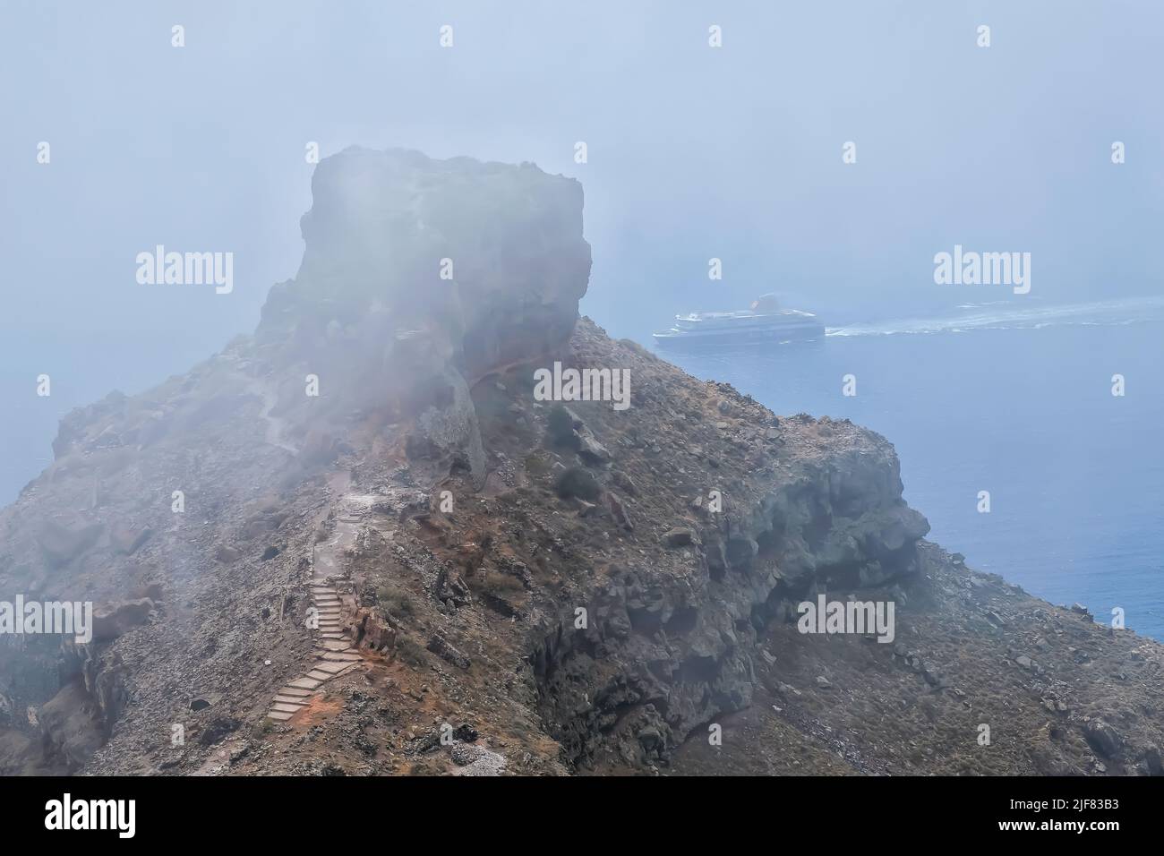 Santorini, Grèce - 13 mai 2021 : le célèbre rocher de Skaros et un ferry approchant l'île de Santorini par temps brumeux Banque D'Images